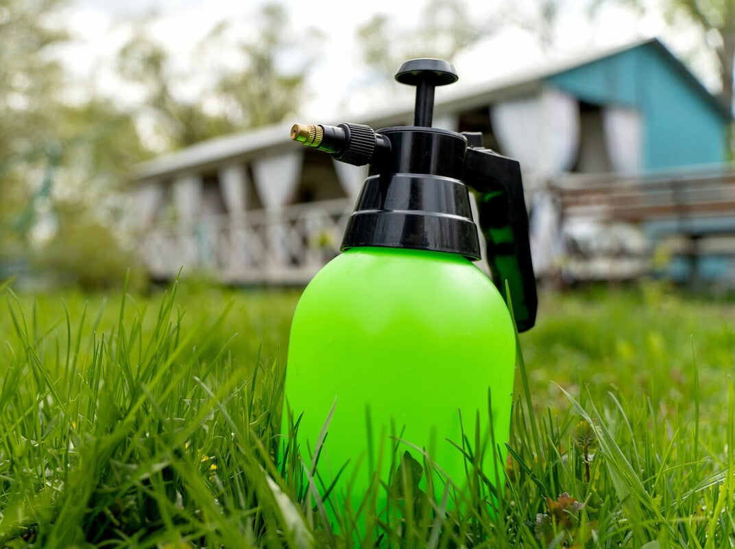 green bottle containing the best mosquito repellent for a yard sitting in a garden