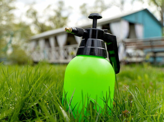 green bottle containing the best mosquito repellent for a yard sitting in a garden